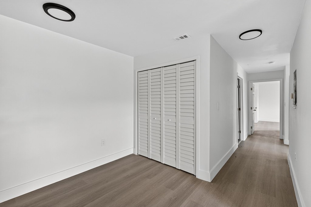 A long hallway with a white door and a white wall.