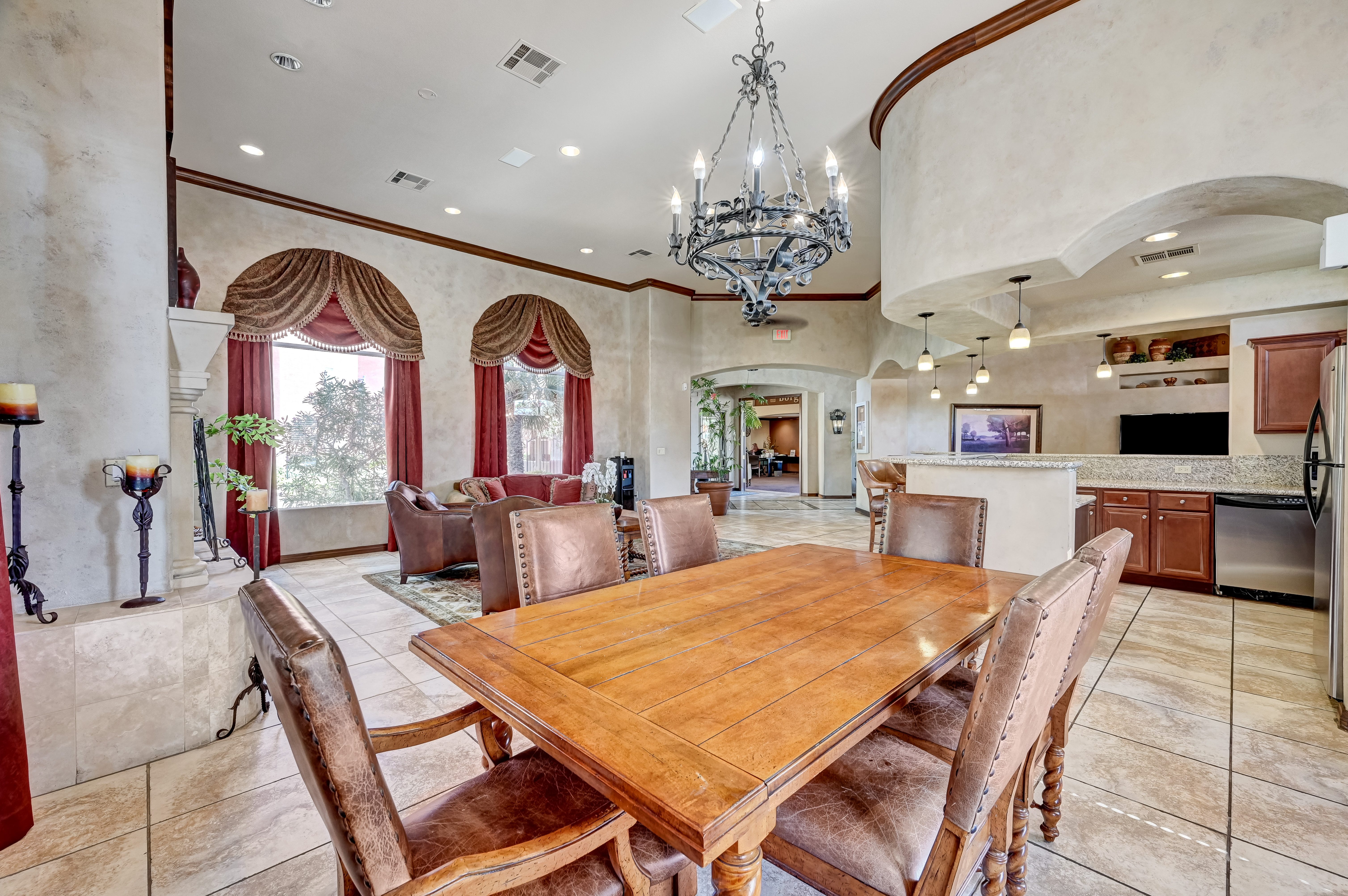 A large wooden dining table surrounded by brown chairs in a room with a chandelier.
