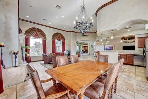 A large wooden dining table surrounded by brown chairs in a room with a chandelier.