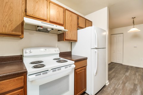 A white stove and refrigerator in a kitchen with wooden cabinets.