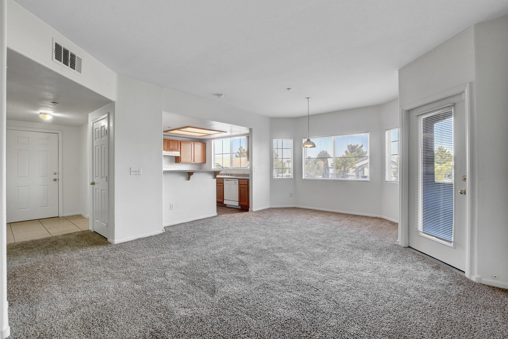 an empty living room with a door to a kitchen