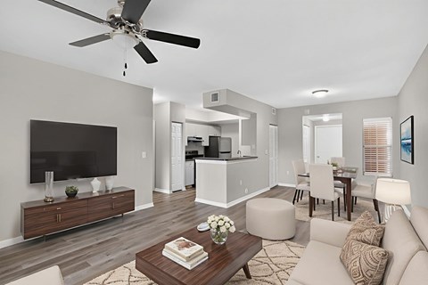 A modern living room with a flat screen TV, a coffee table, and a ceiling fan.