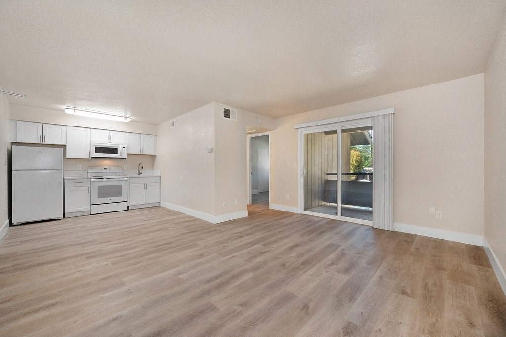 a spacious living room with a kitchen in the background