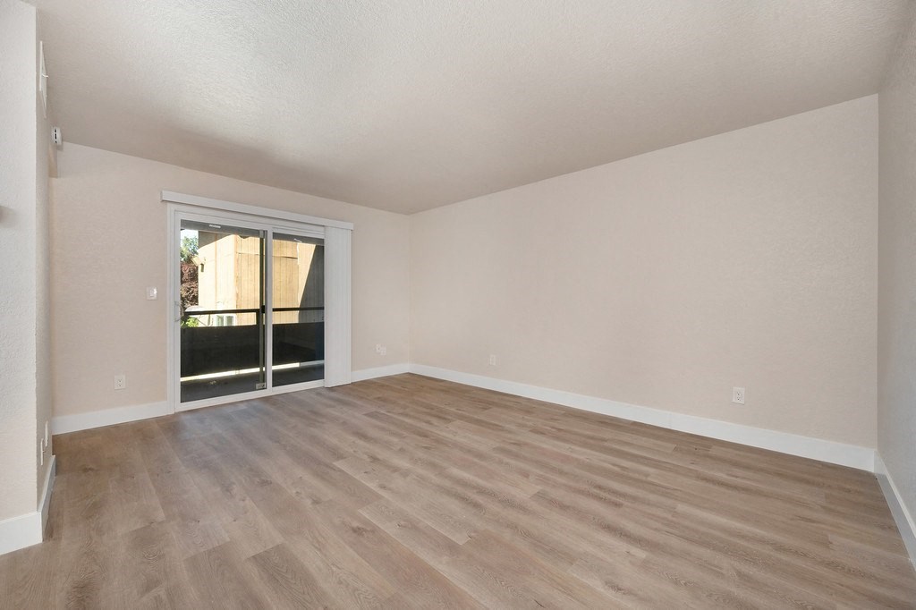 a bedroom with hardwood floors and a sliding glass door to a balcony