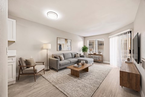 A living room with a grey couch, a wooden coffee table, and a flat screen TV mounted on the wall.