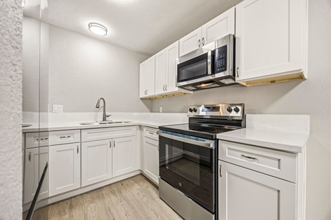 A kitchen with white cabinets and appliances.