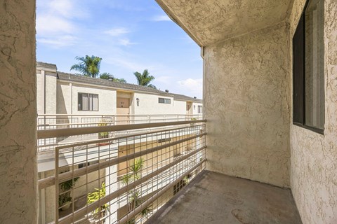 A balcony with a metal railing and a view of apartment buildings.