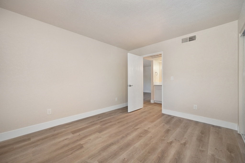 a bedroom with hardwood floors and beige walls