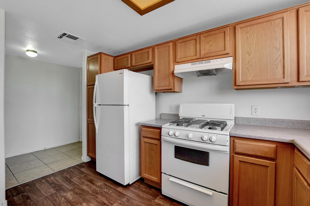 an empty kitchen with white appliances and wooden cabinets