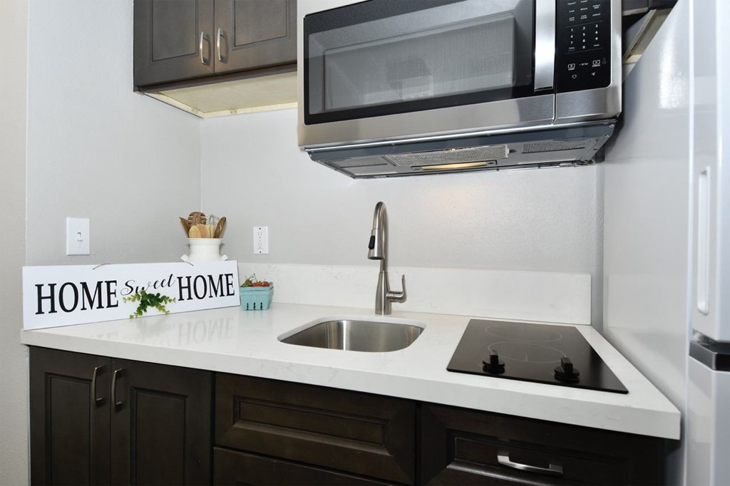 A kitchen with a white countertop and a black microwave above it.