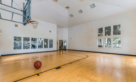 A basketball is on the court in an empty gym.