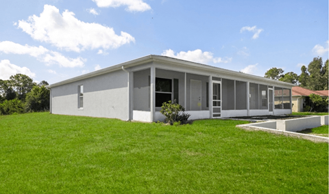A modern house with a grey exterior and a green lawn in front.