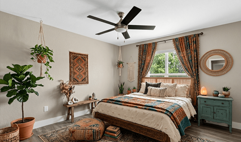A bedroom with a bed, a ceiling fan, and a window with curtains.