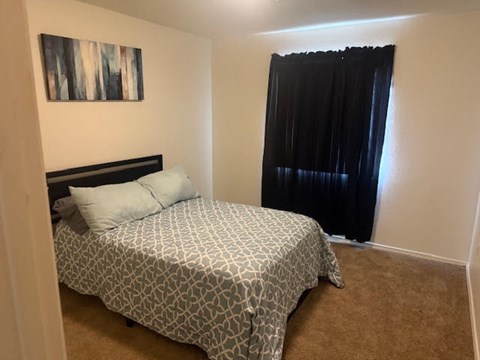 A bedroom with a patterned bedspread and a black headboard.