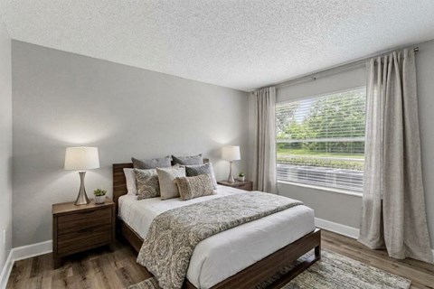 A bedroom with a large bed and two lamps on either side of the bed.