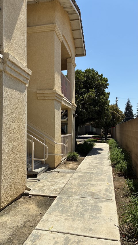 A concrete staircase with a metal railing leads up to a building.