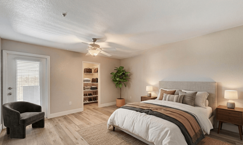 A bedroom with a bed, chair, and a plant.