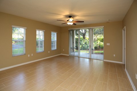 an empty living room with a ceiling fan and sliding glass doors