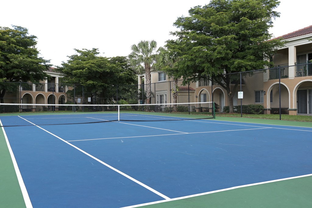 a blue tennis court in front of an apartment building