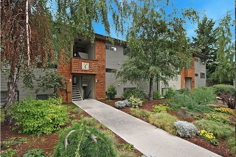 a building with a sidewalk and trees in front of it