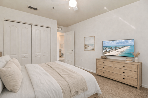 A bedroom with a bed, dresser, and a painting of a beach scene on the wall.