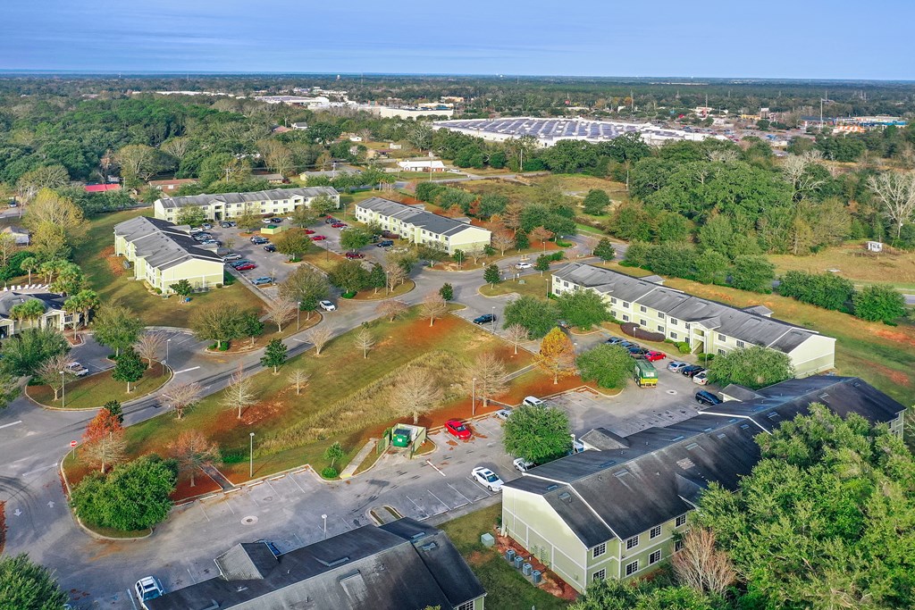 A large parking lot is surrounded by buildings and trees.