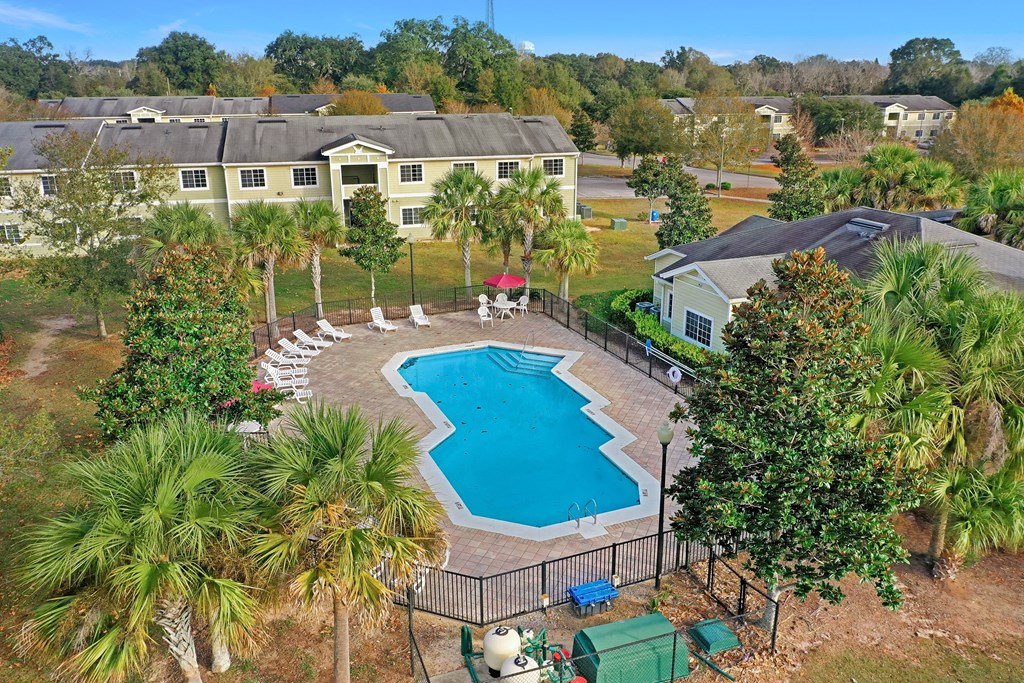 A pool surrounded by a fence and trees.