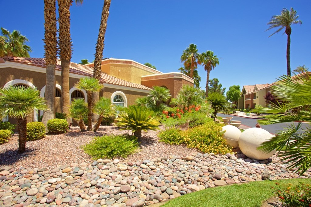 a house with palm trees and rocks in front of it
