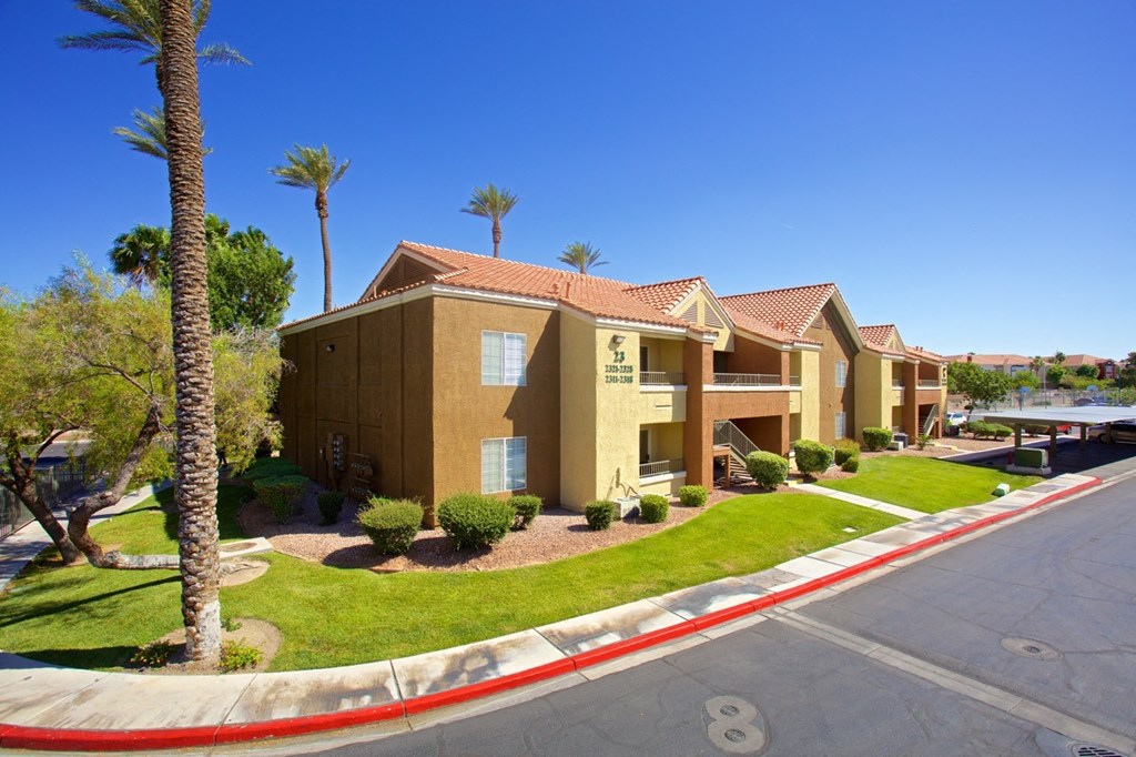 a row of yellow houses with palm trees and a street