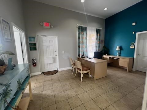 A room with a desk, chair, and a window with curtains.