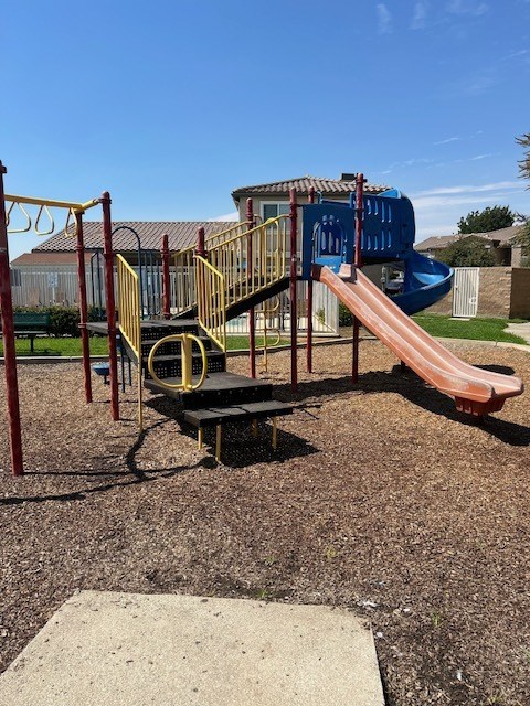 A playground with a blue slide and a yellow and black play structure.