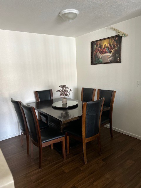 A dining table with four chairs and a vase with flowers on it.
