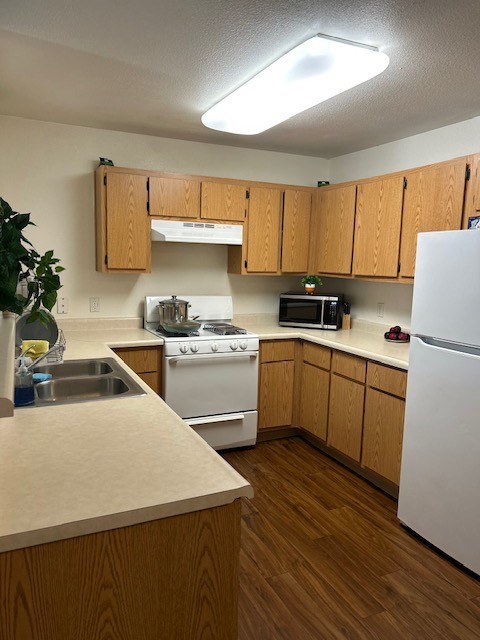 A kitchen with wooden cabinets and white appliances.