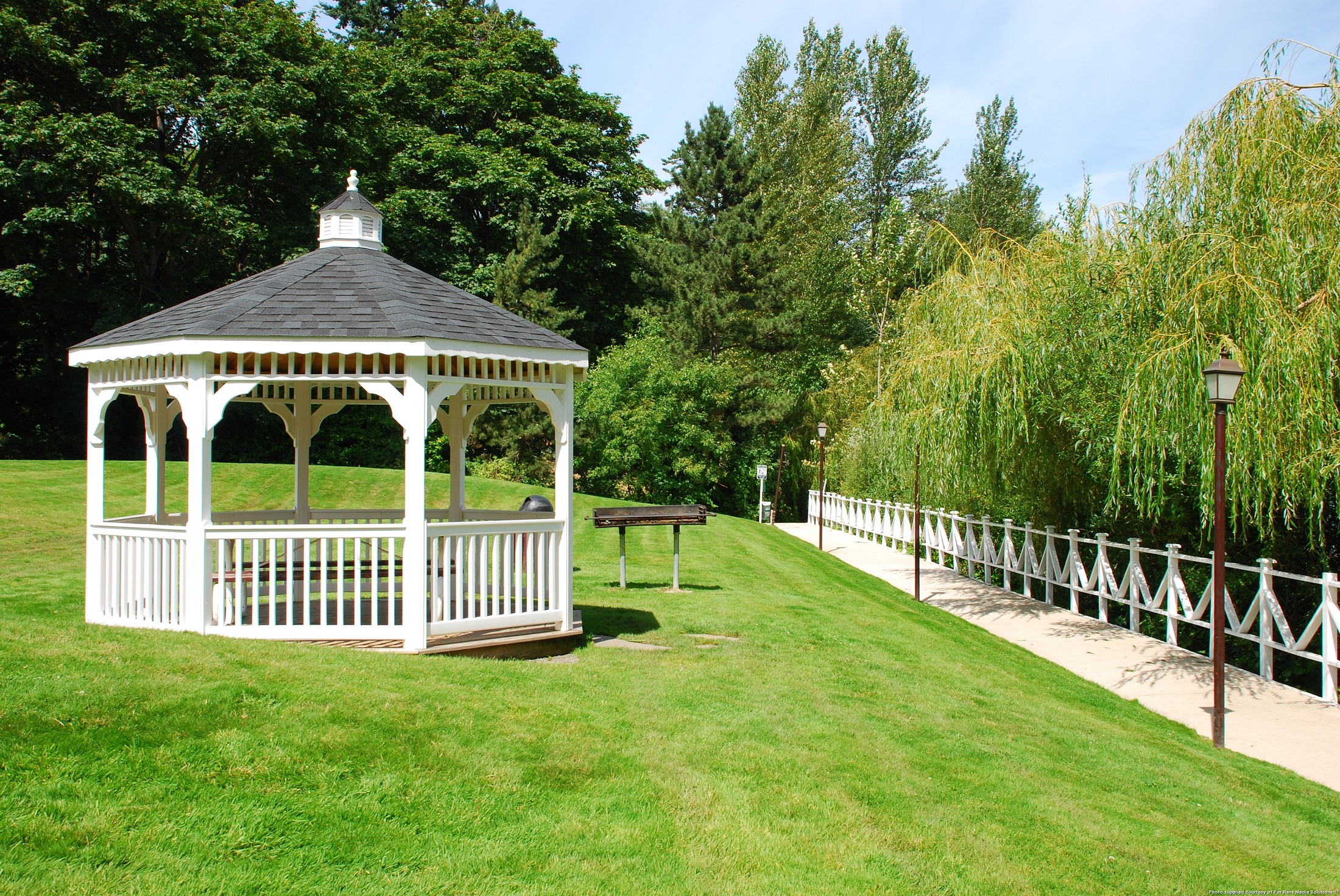 a gazebo in the middle of a lawn with a bench