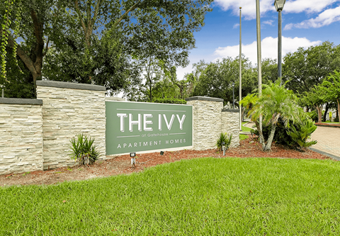 A sign that says "The Ivy Apartment Homes" in front of a stone wall.