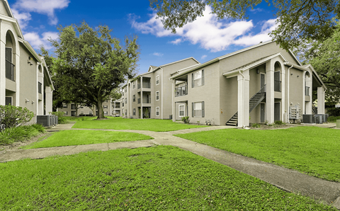 A row of apartment buildings with green lawns in front.