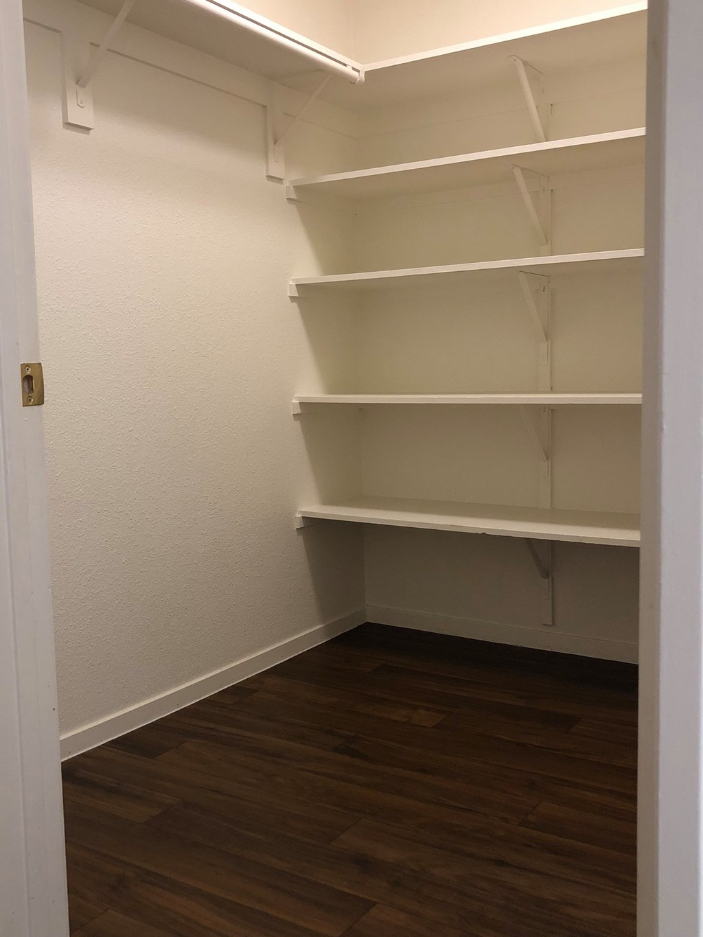 Empty room with white shelves and wooden floor.