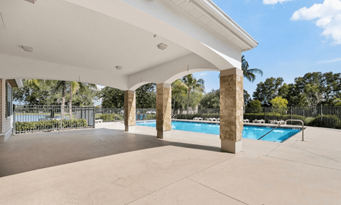 A pool area with a white roof and a fence in the background.