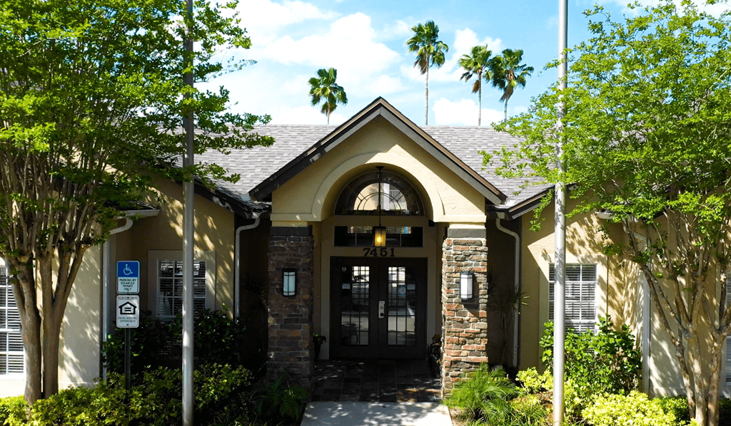 A building with a black door and windows surrounded by trees.