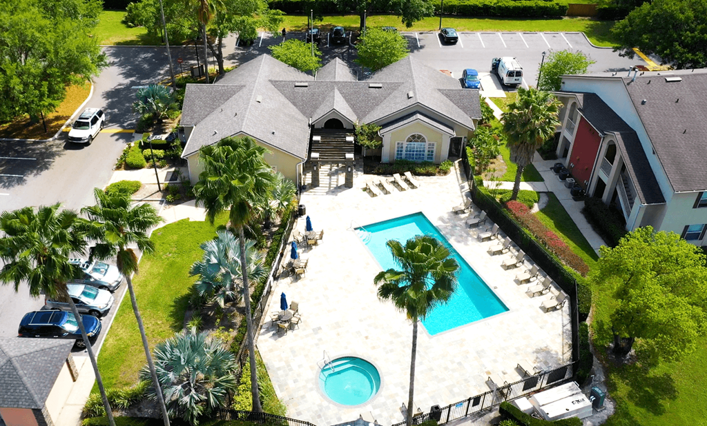 A swimming pool surrounded by palm trees and a house.