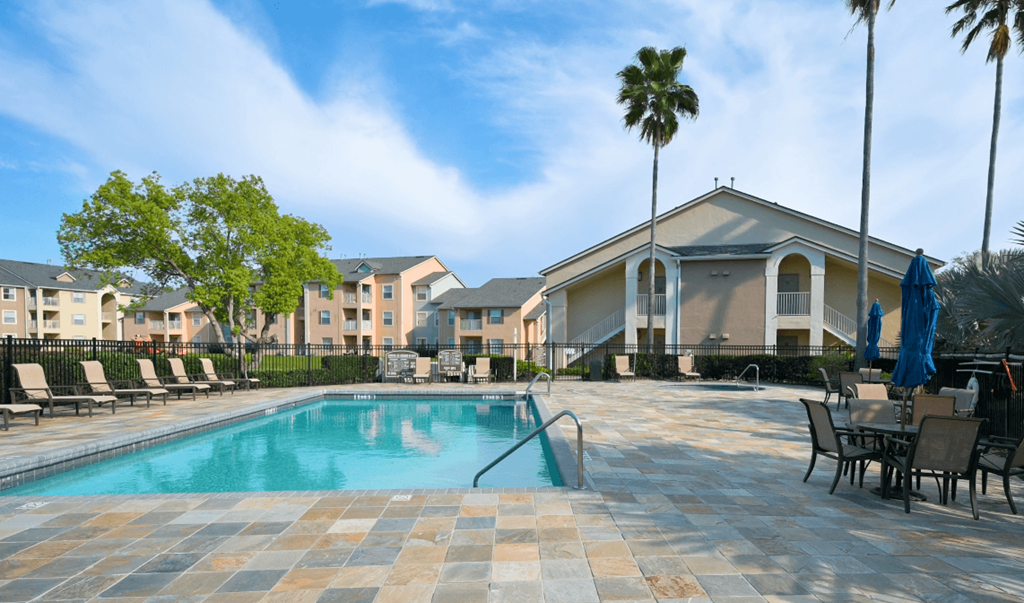 A swimming pool surrounded by chairs and umbrellas in a residential area.