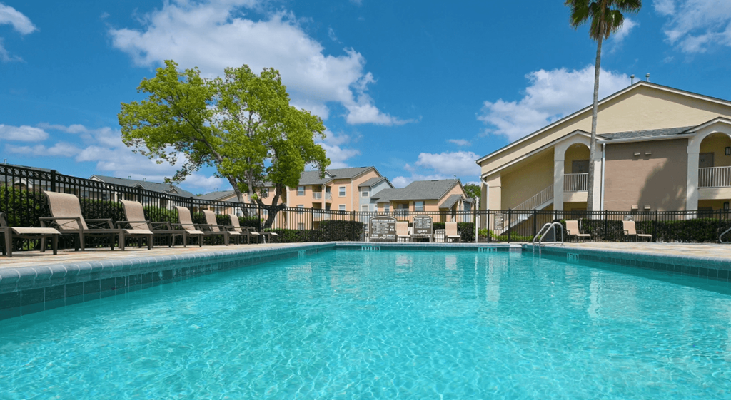 A swimming pool surrounded by lounge chairs and palm trees.