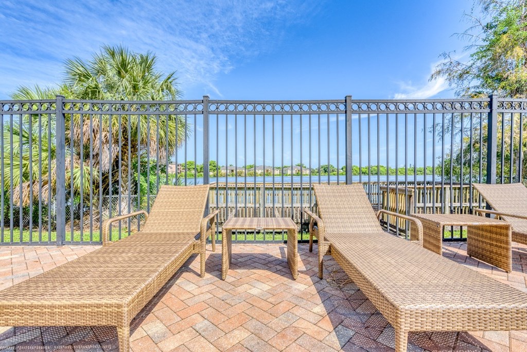 A patio with a table and chairs overlooking a body of water.