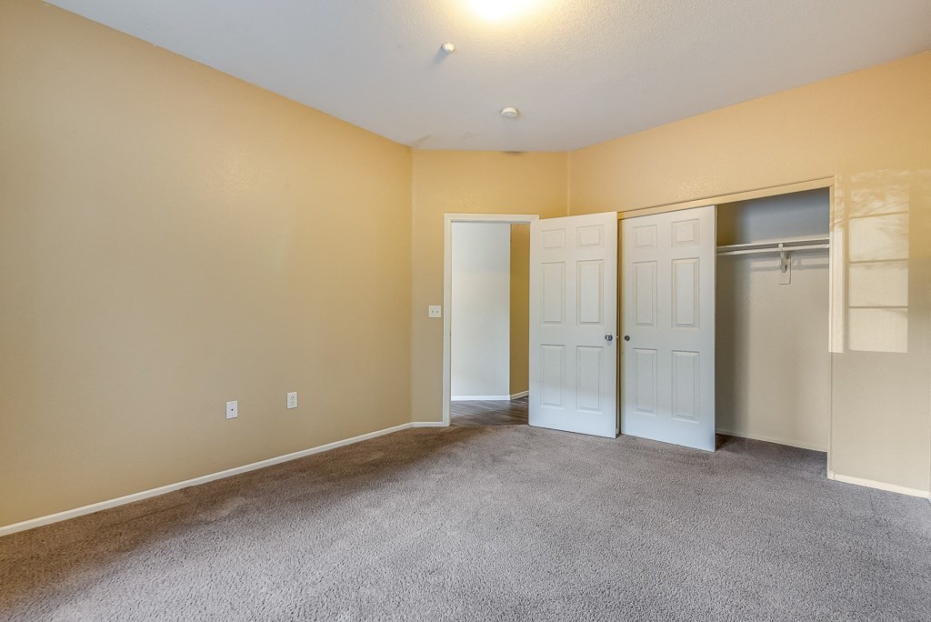 an empty living room with two doors and a closet