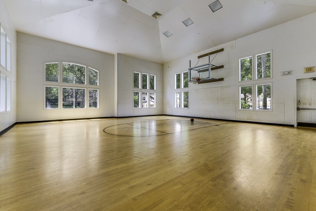 A large empty room with wooden floors and windows.