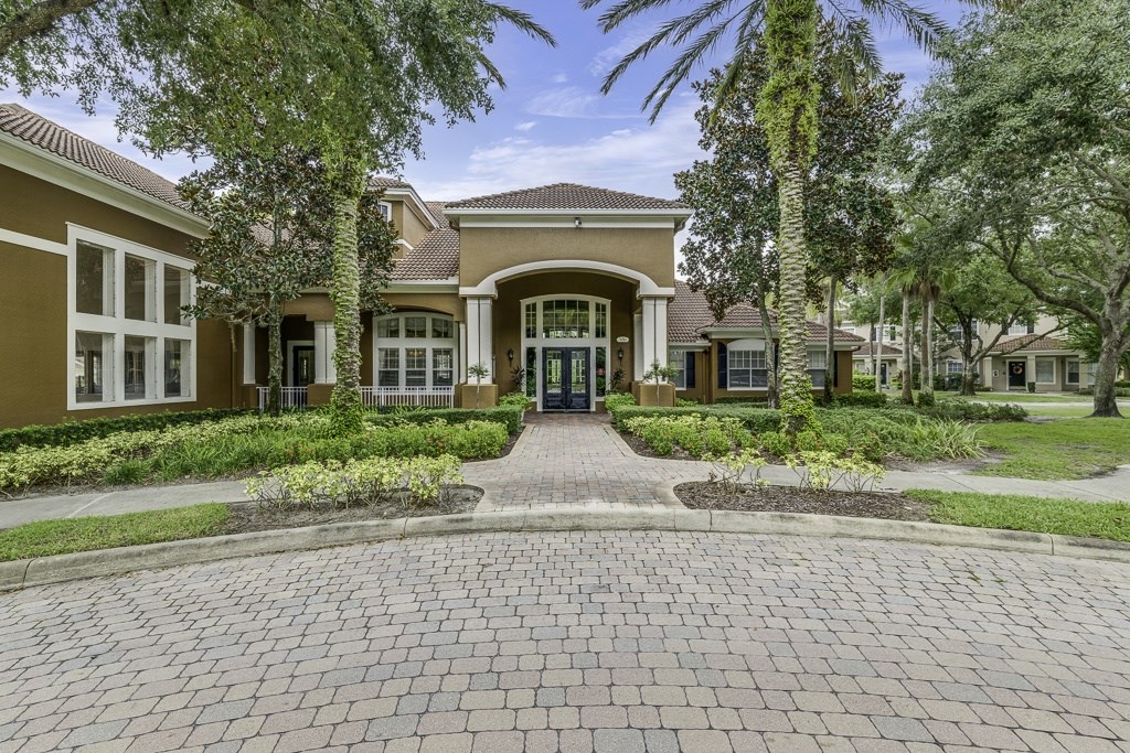 A brick pathway leads to a building entrance surrounded by greenery.