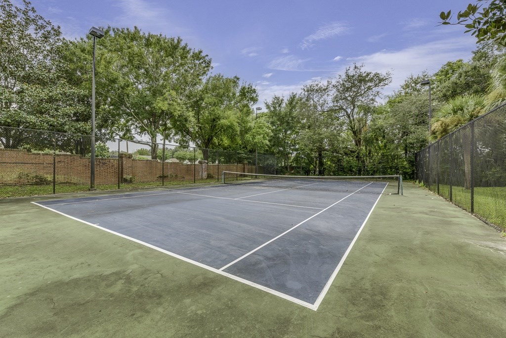 A tennis court surrounded by a fence and trees.