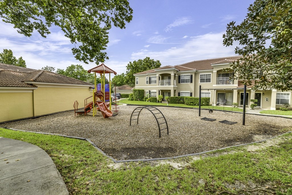 A playground with a swing set and a sandbox in front of a building.