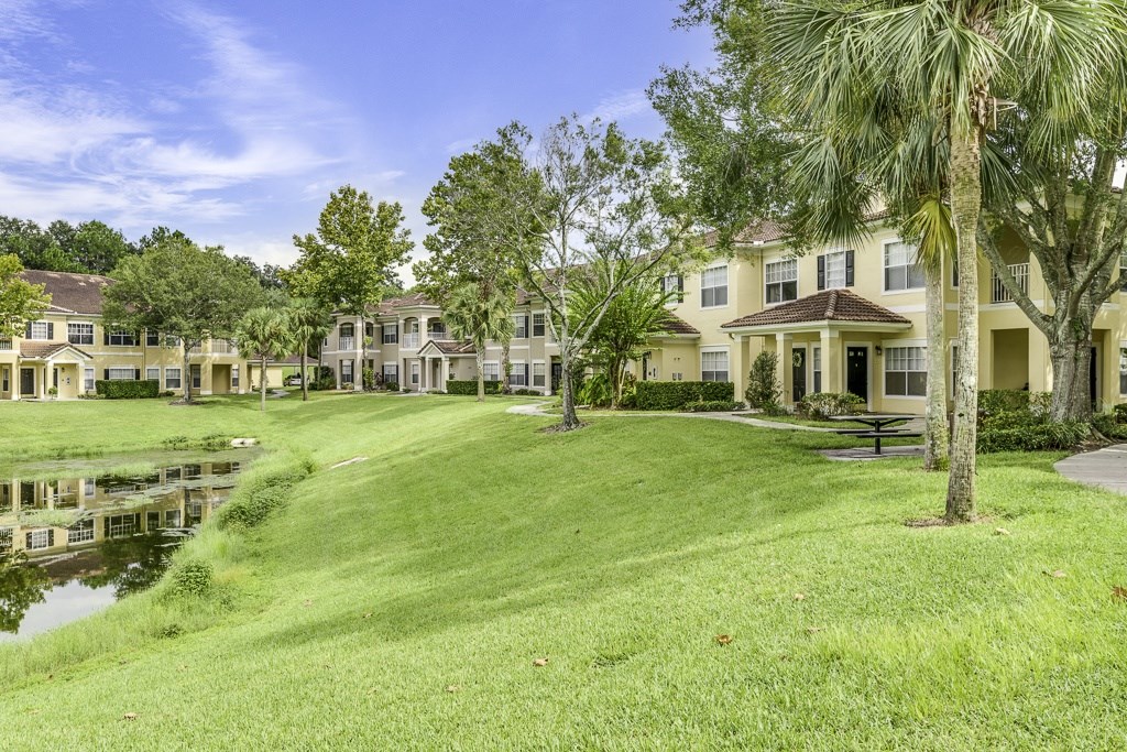 A row of houses with a pond in front of them.