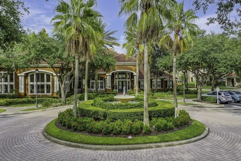 A building with a landscaped front yard and palm trees.